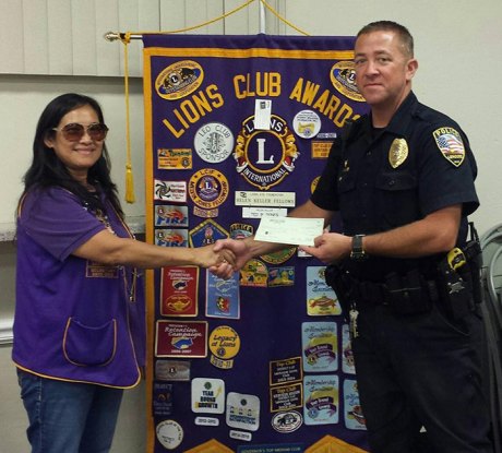 Officer Kevin Cosper accepts a donation from Lemoore Lions Club President Ever Casas.